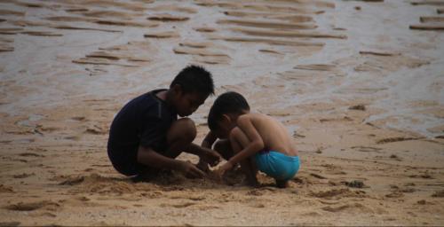 Kids playing in the sand on the beach.